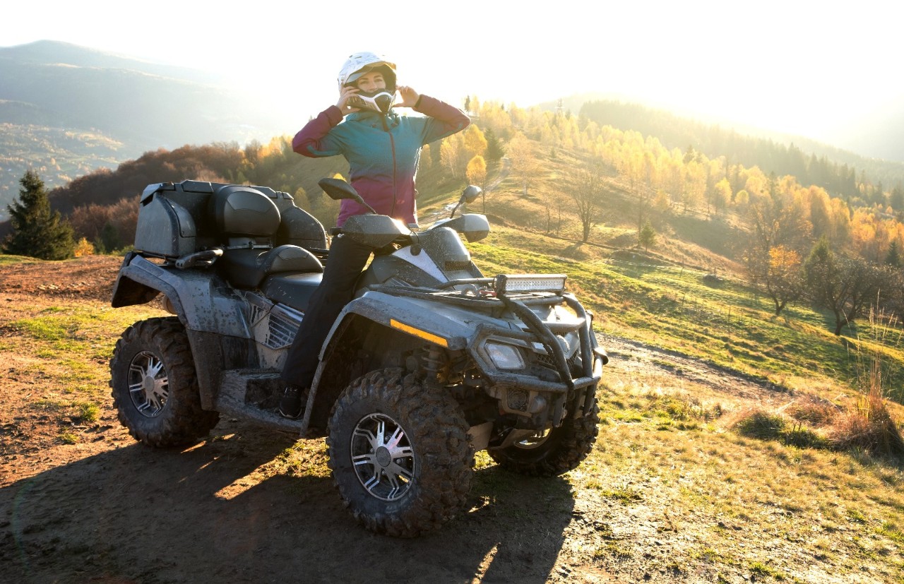 Dame kjører ATV på fjellet. Foto.