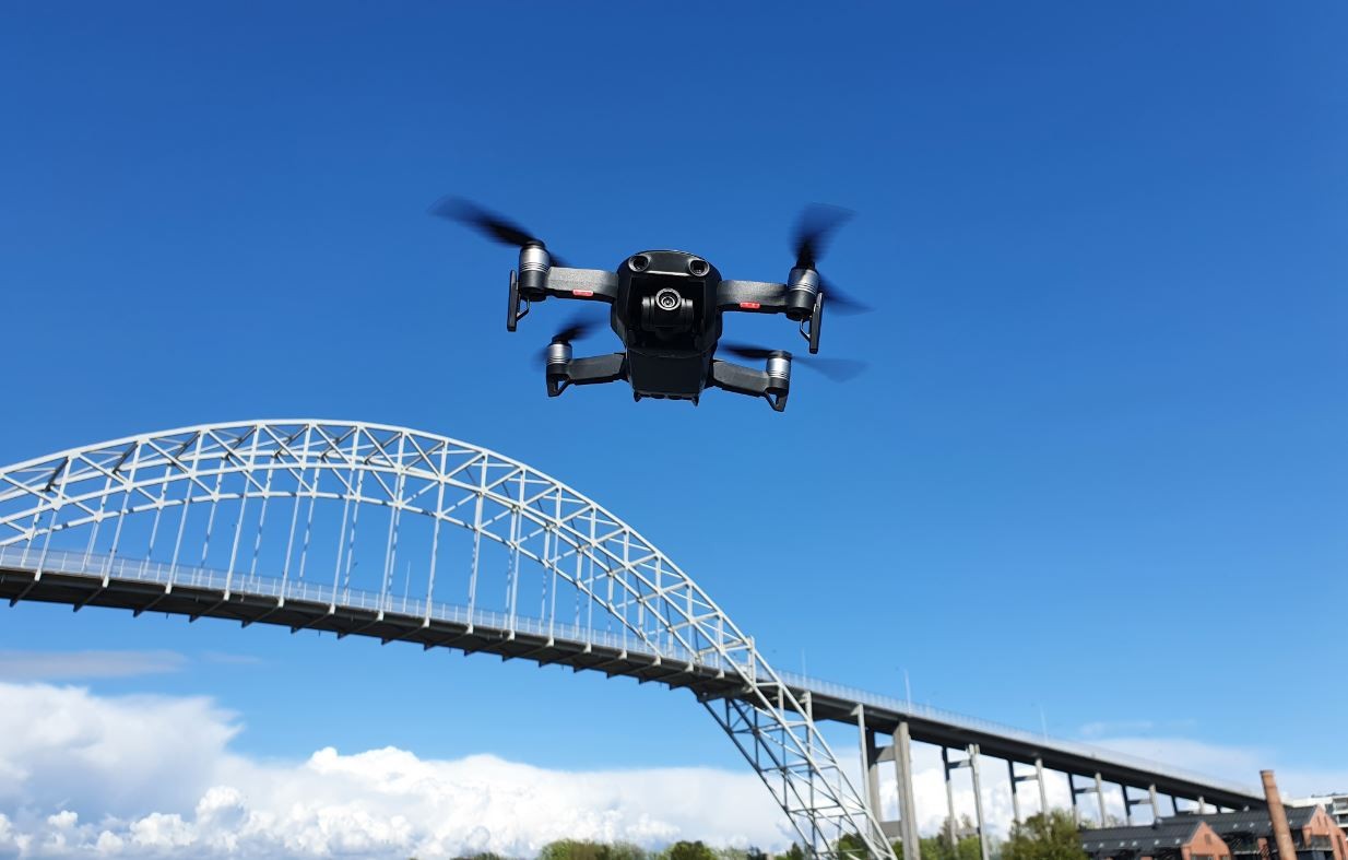 drone i lufta med bro i bakgrunnen