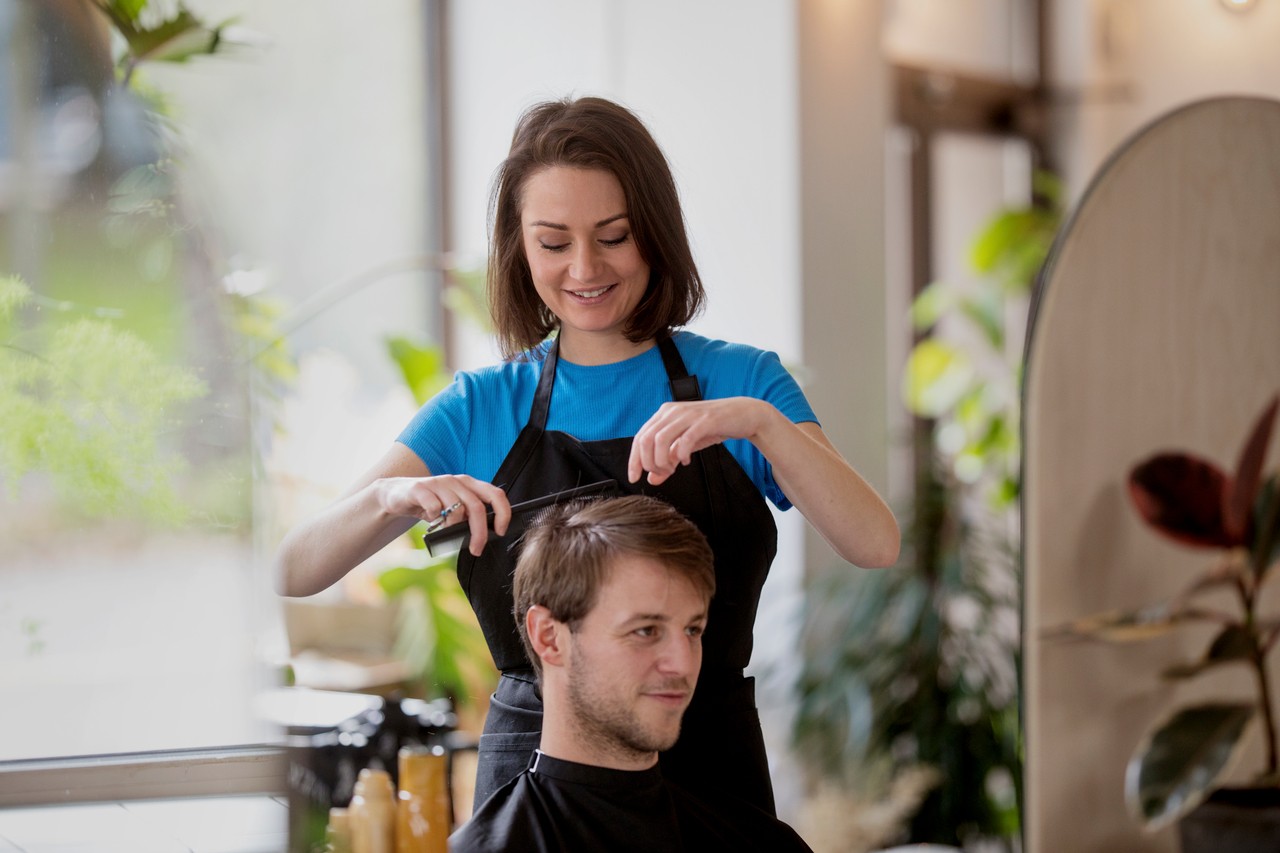 frisør som klipper mann er forsikret mot belastningsskader